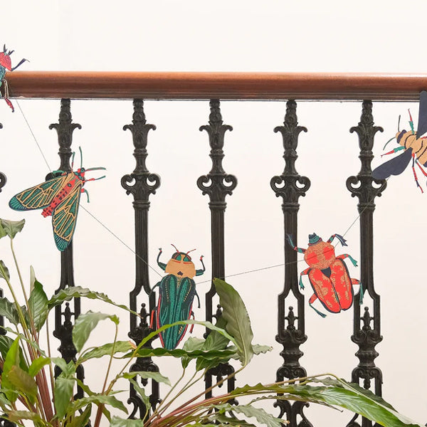 Decorative paper insects on a railing with a white background