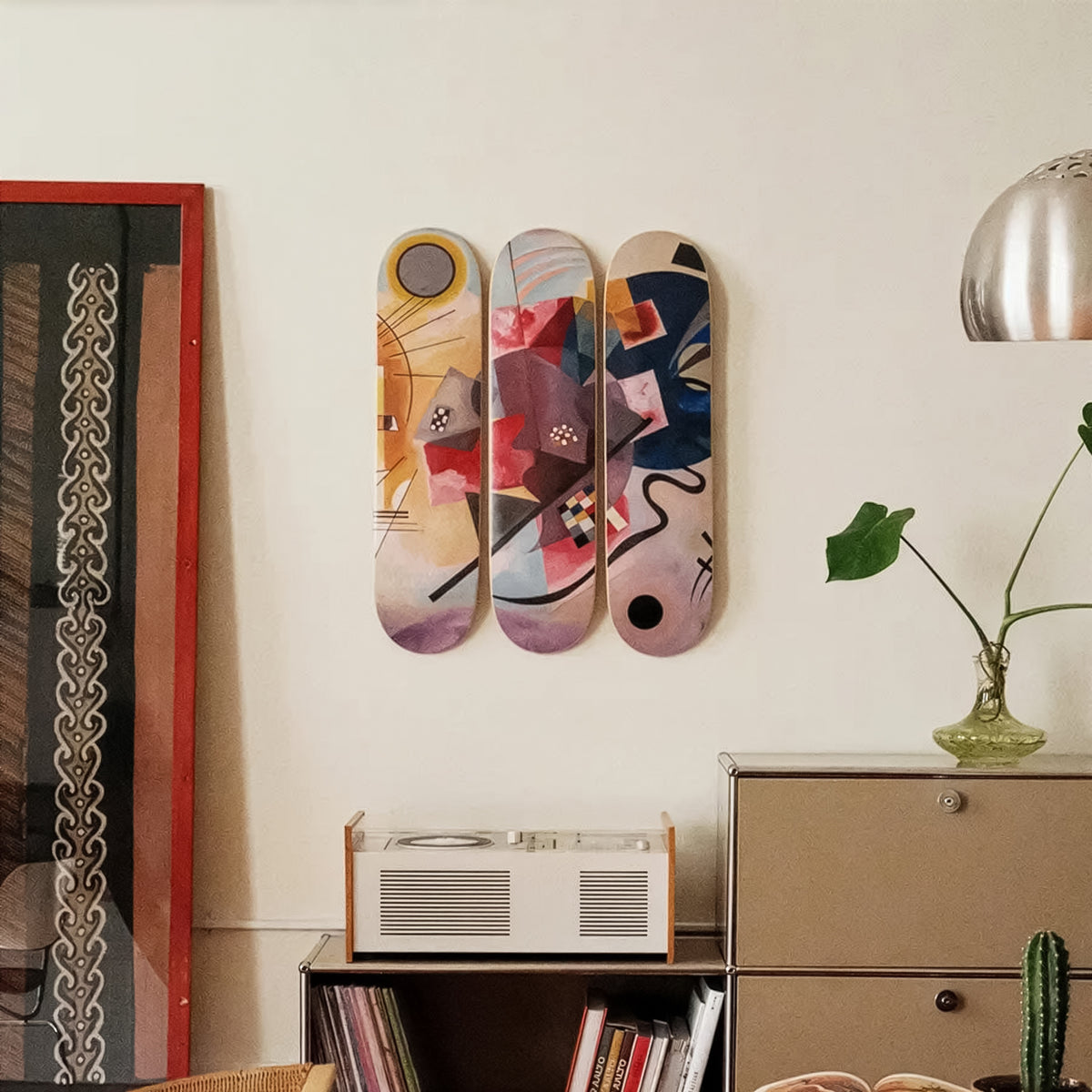 Three colorful skateboard decks on a wall above a radio and books.