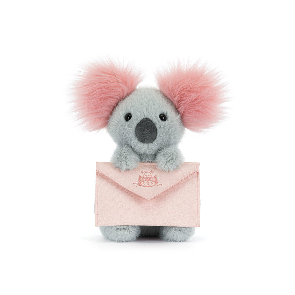 Plush koala holding a pink envelope on a white background
