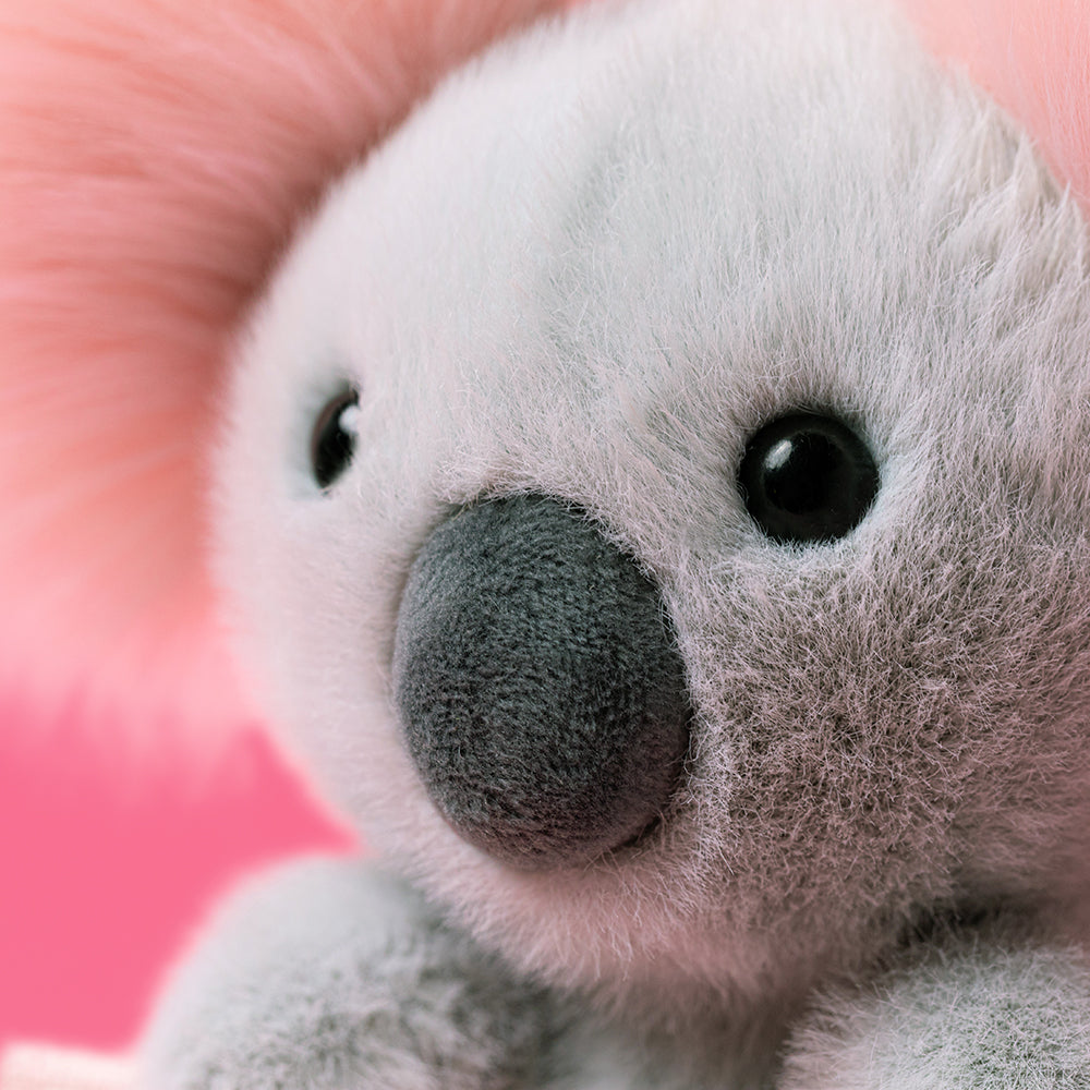 Close-up of a plush koala toy with a pink background