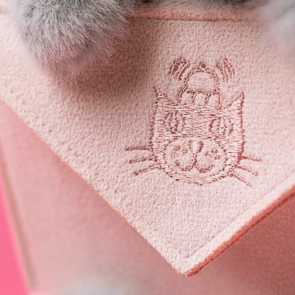 Embroidered design on a pink fabric with a fluffy gray object in the corner.