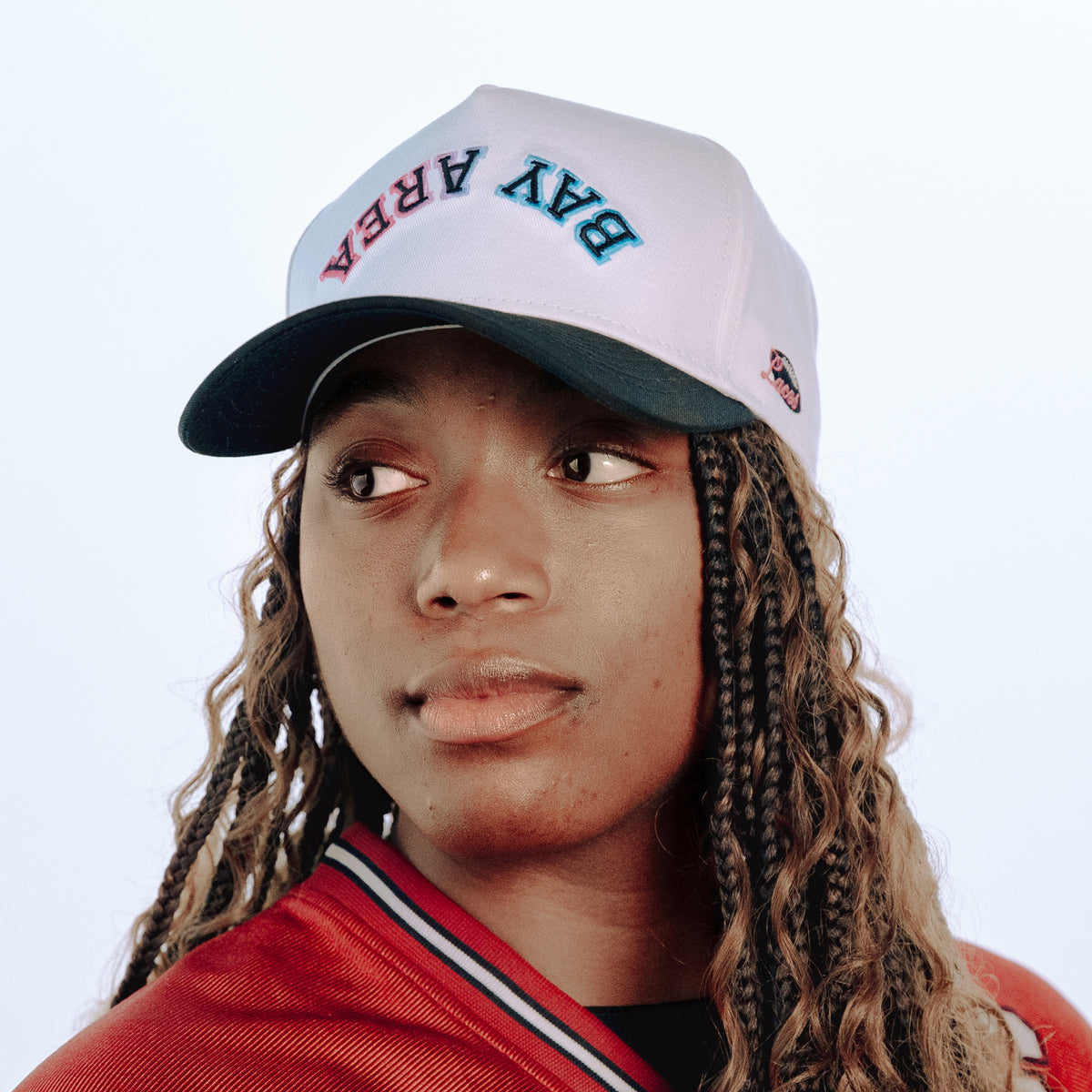 Person wearing a white cap with text and a red jacket on a light blue background