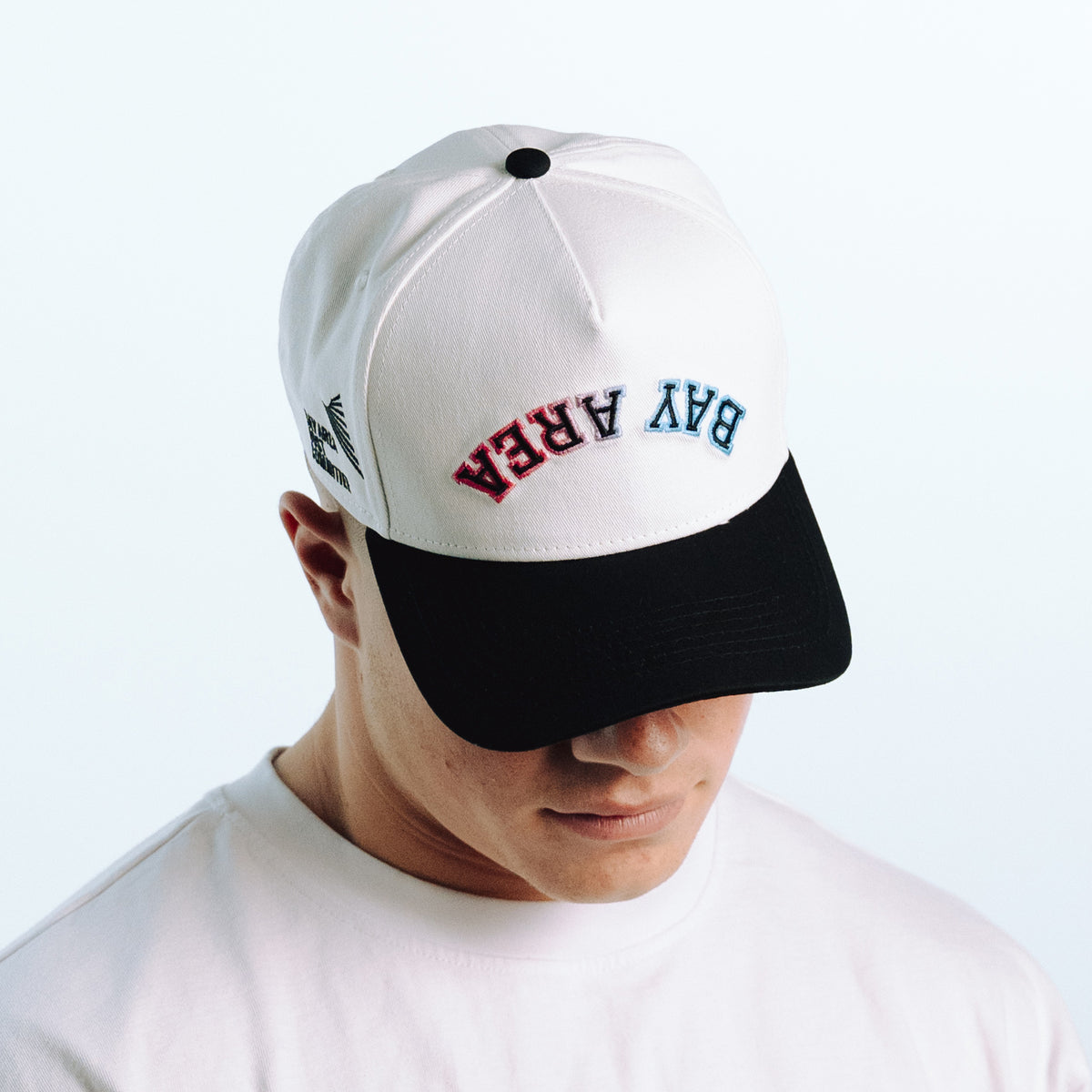 Person wearing a white and black cap with text on a light gray background