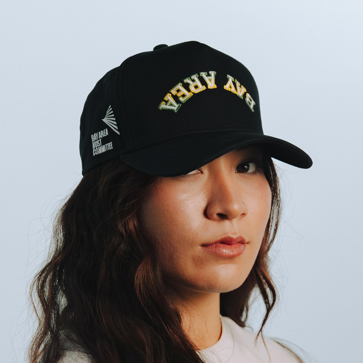 Person wearing a black cap with text and logos on a light blue background