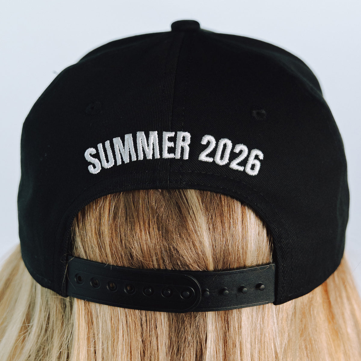Black cap with 'SUMMER 2026' text on a person wearing it.