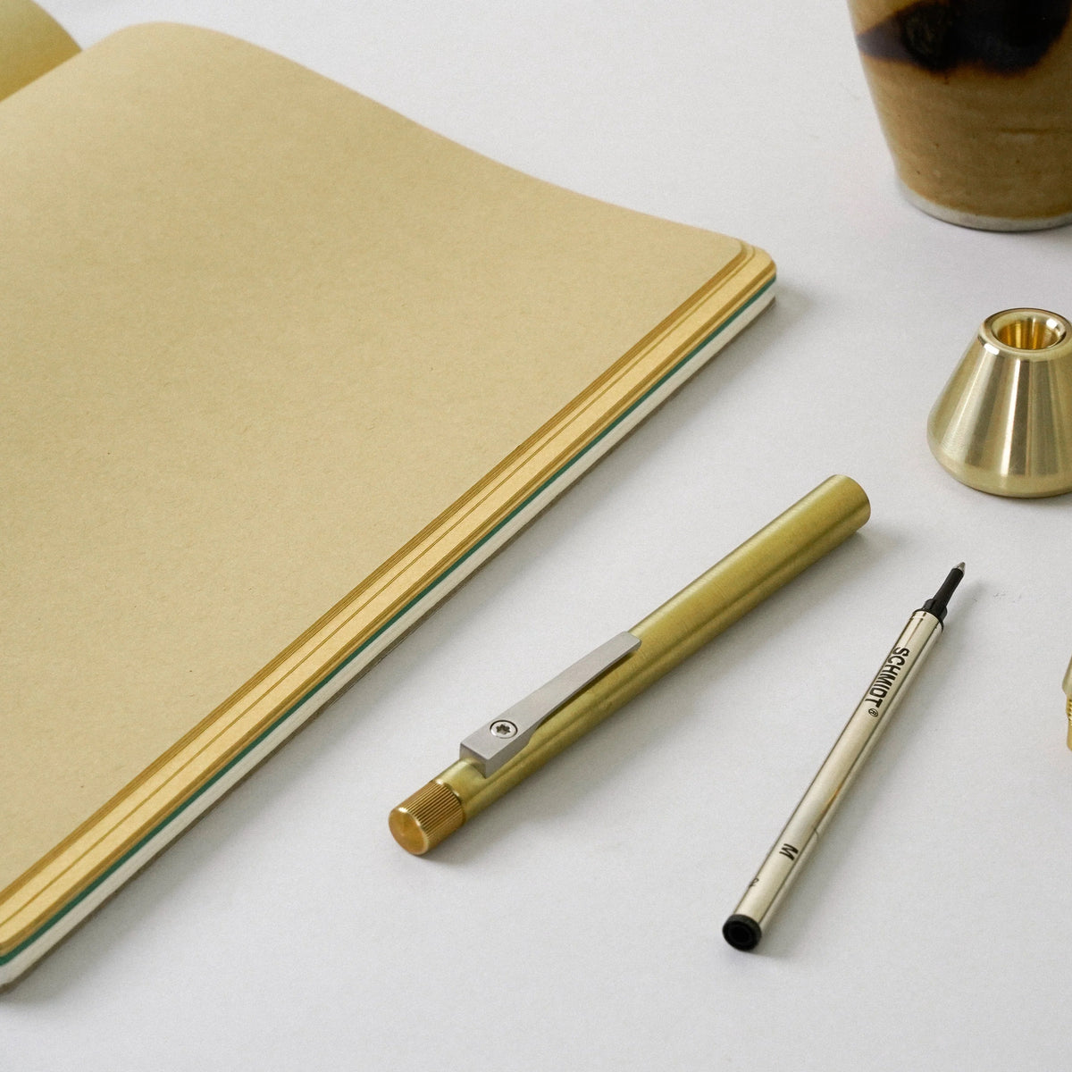 Brass pen and notebook on a white surface