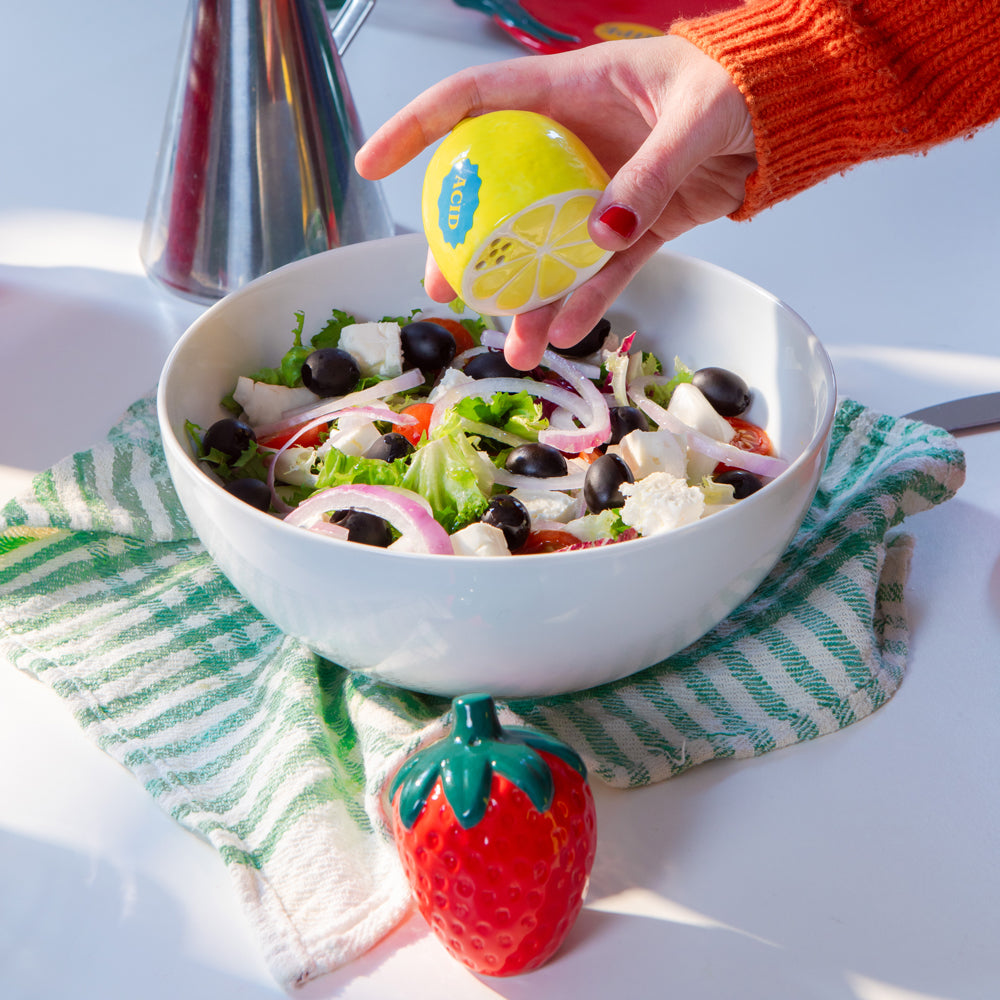 Model using lemon shaker on salad.