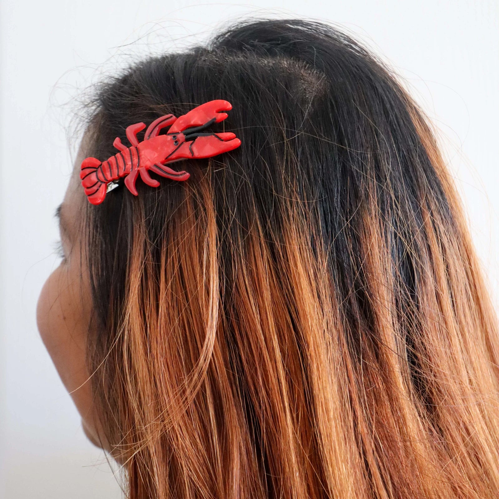 Two red lobster-shaped hair clips on a white background