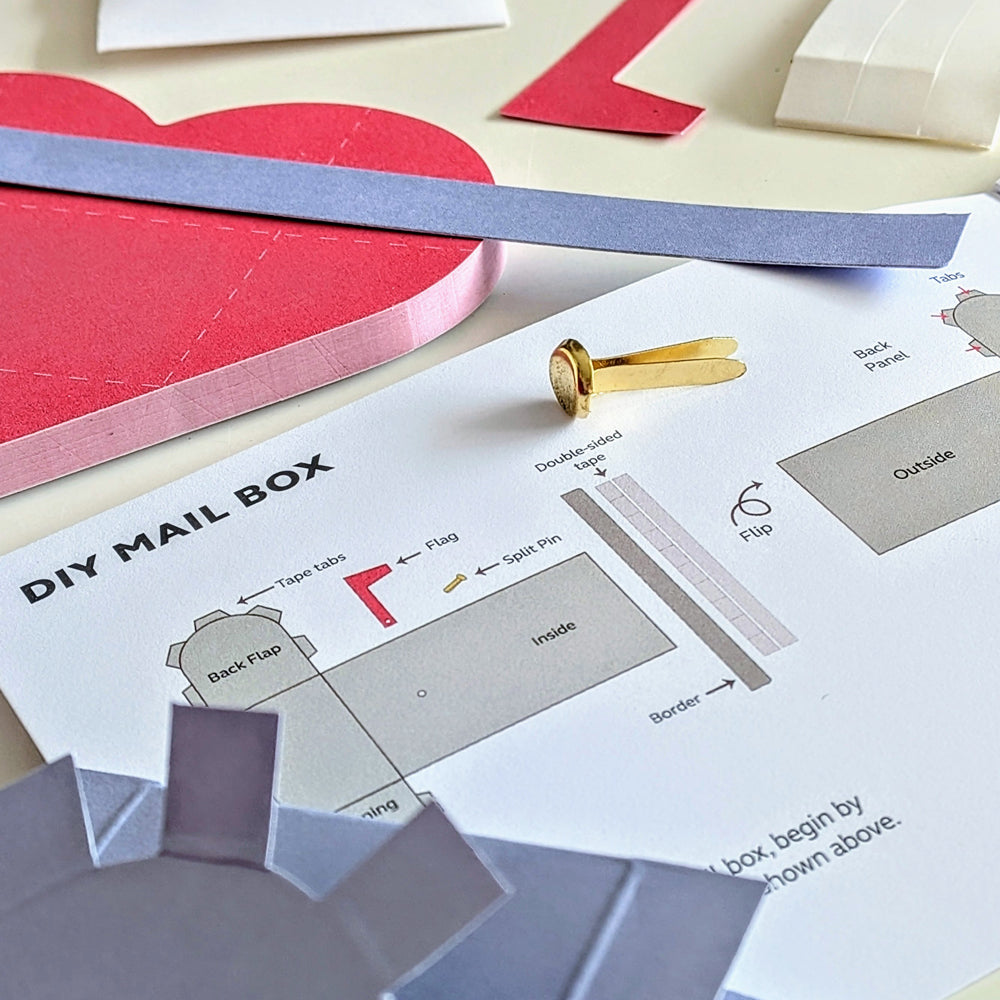 DIY mail box craft project with cut-out pieces and instructions on a table.