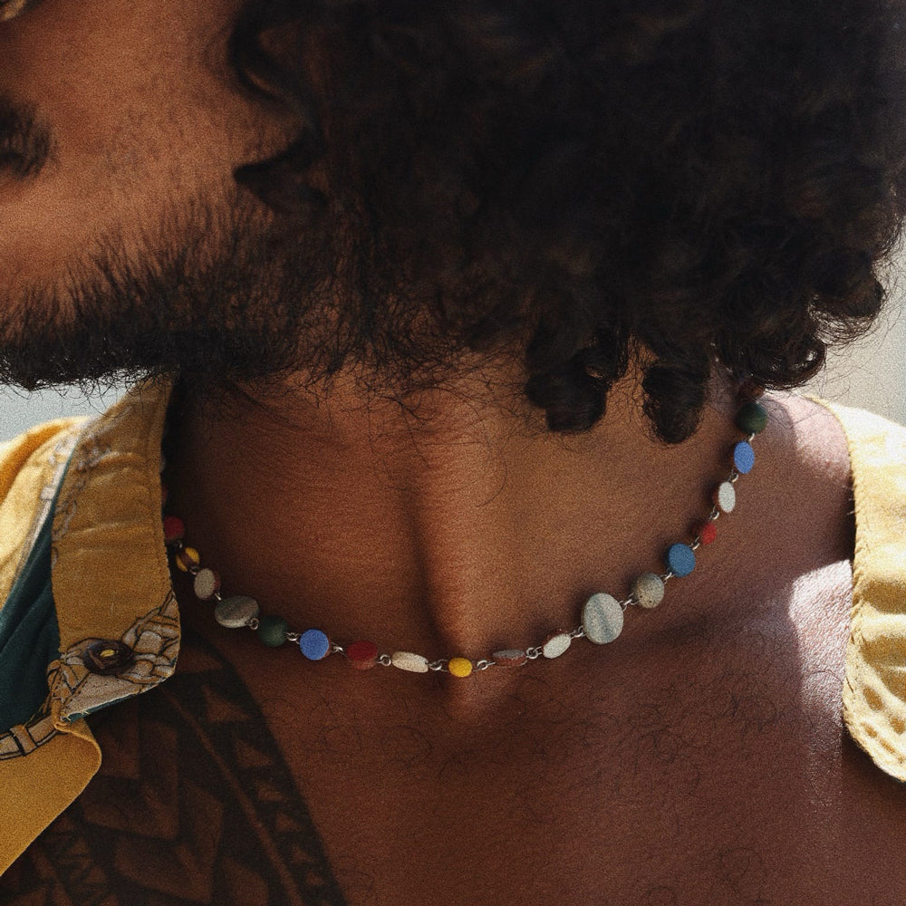 Person wearing a colorful beaded necklace with a blurred background