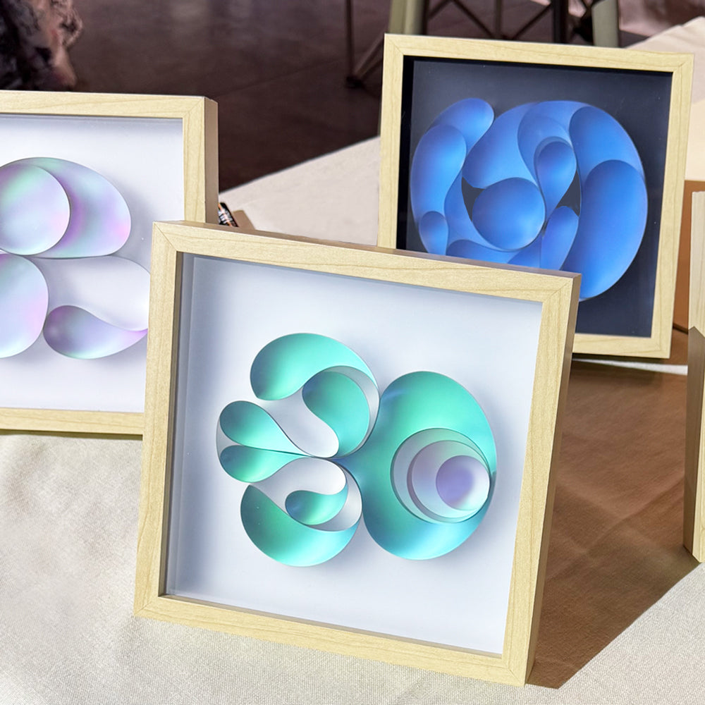 Three framed abstract art pieces on a table