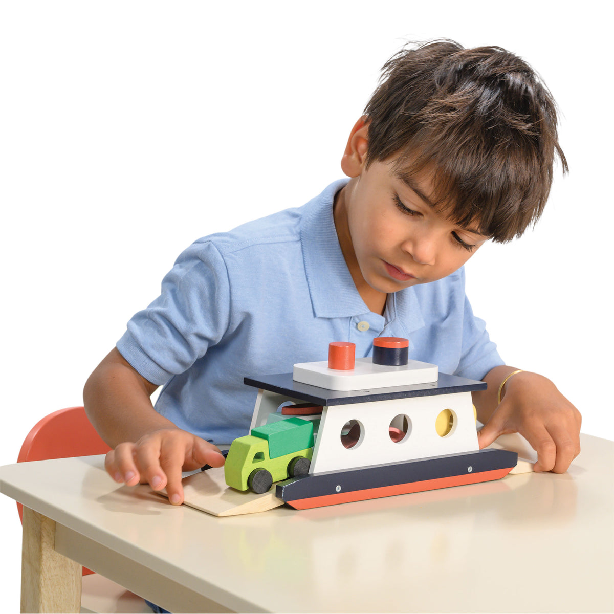 Child playing with a toy car and ramp set on a white background