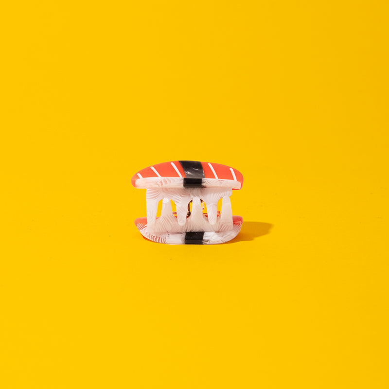 Hair clip with red and black striped design on a yellow background