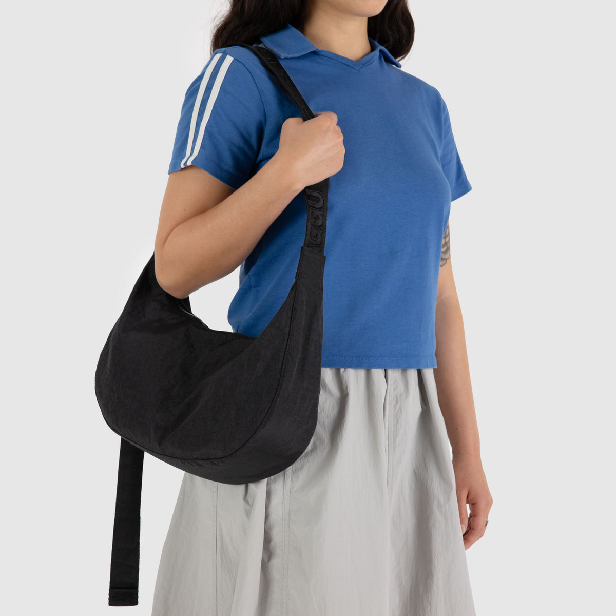Person wearing a blue shirt and carrying a black bag on a white background