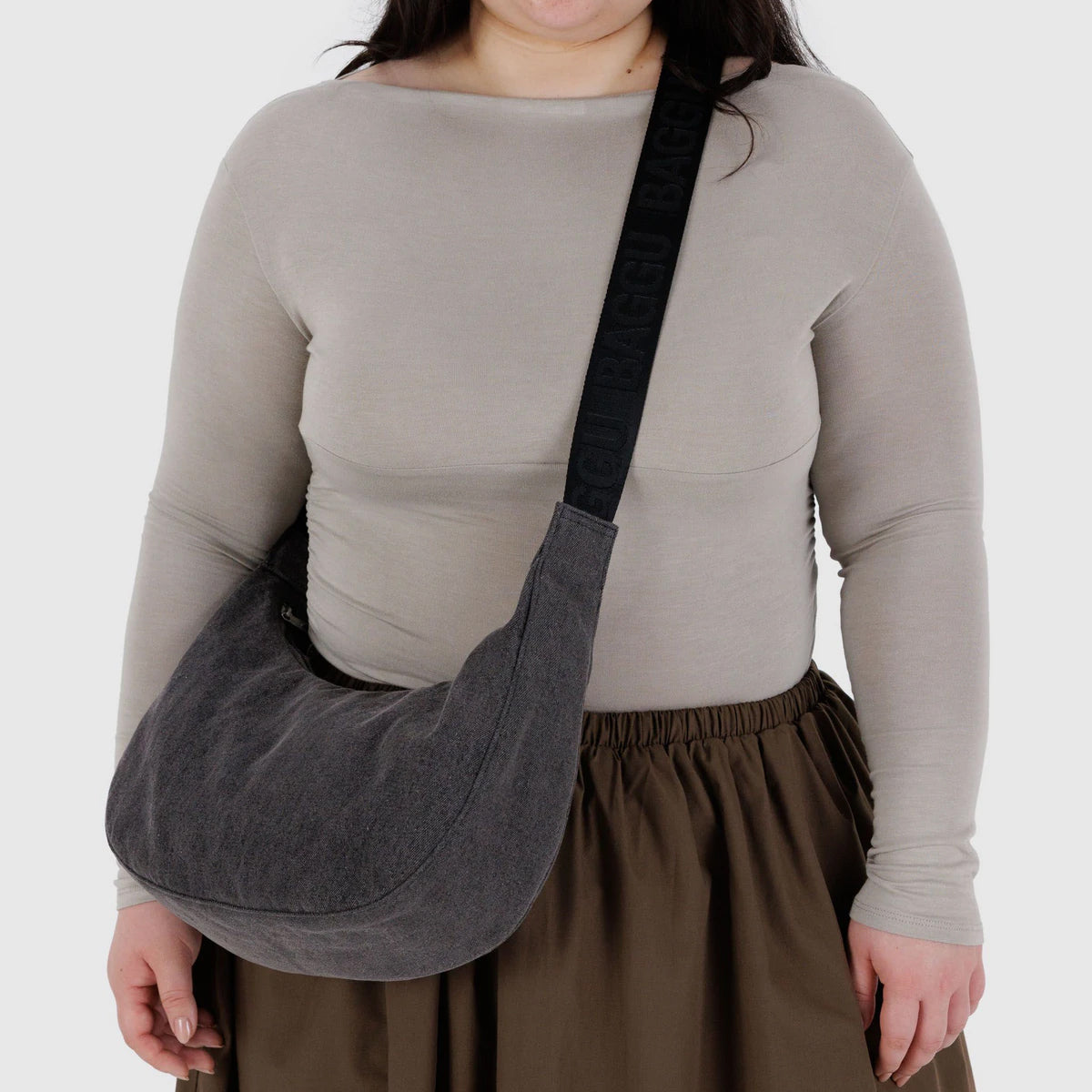 Person wearing a shoulder bag with a plain background