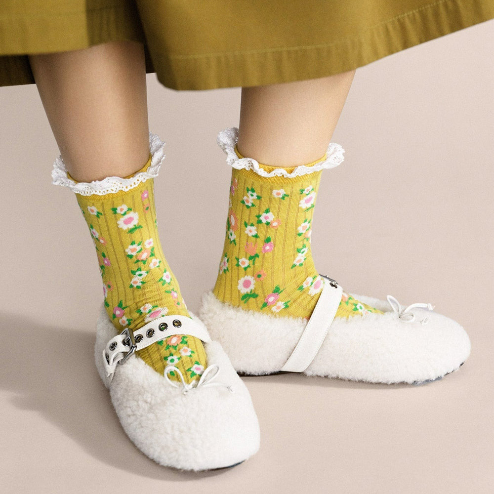 Yellow socks with floral pattern and white lace trim on a white background