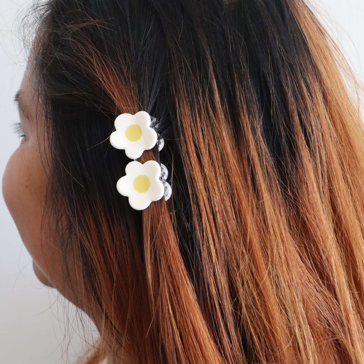 Hair claws with white flowers in a person's hair against a white background