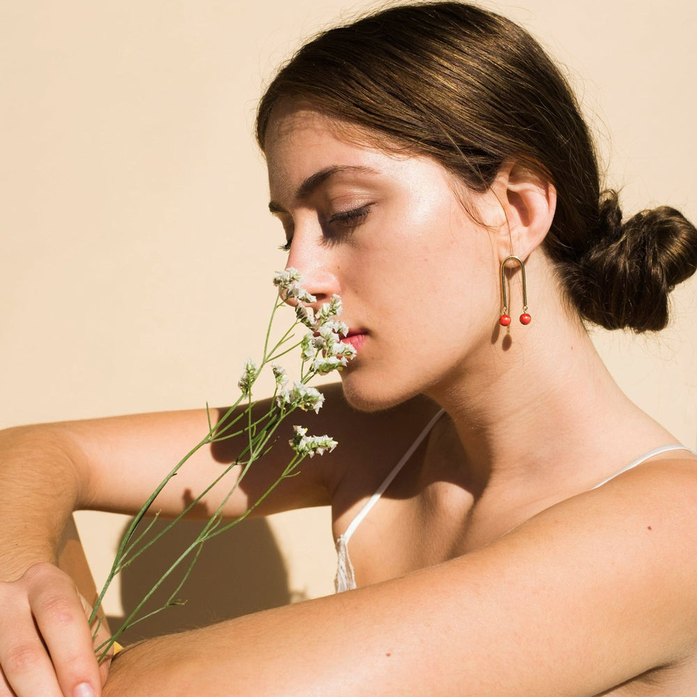 Model smelling flowers wearing earrings.