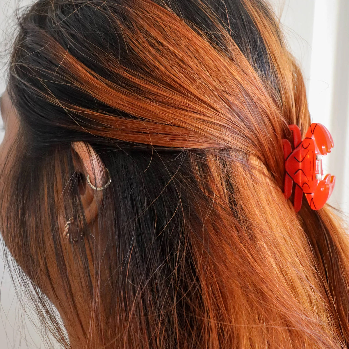 Person with red and black hair styled with a mini crab hair clip.