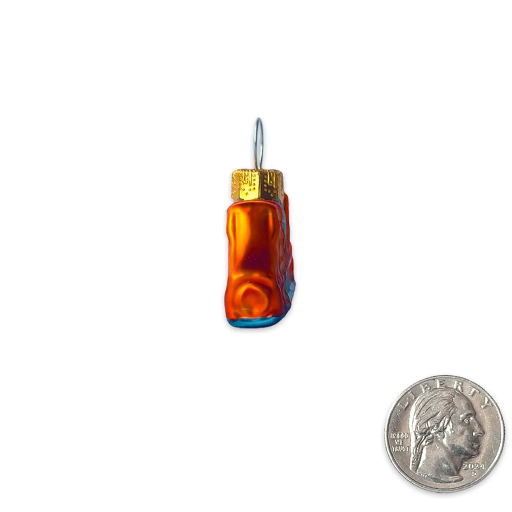 A small glass ornament shaped like a textured bottle with a gold cap and blue base, shown on a white background with a US quarter coin in the lower right for scale.