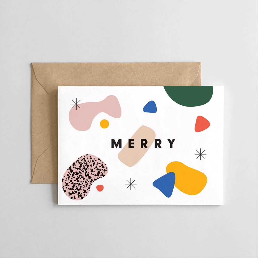 A square brown kraft paper gift box, featuring a white label with colorful abstract shapes and the word 'MERRY' in black.