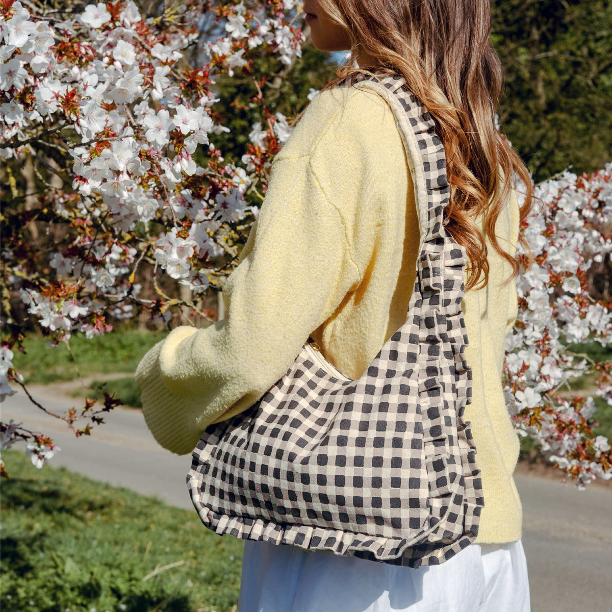 Woman with a momo bag standing in front of cherry blossom trees