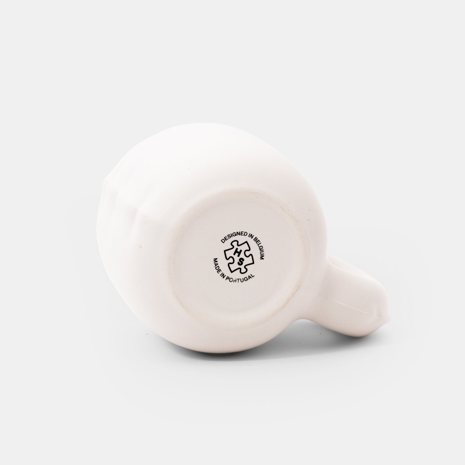 A minimalist ceramic mug with a unique, rounded handle and a matte finish, shown on a clean white background.