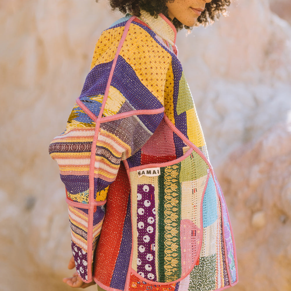 Person wearing a colorful quilted jacket with a blurred natural background