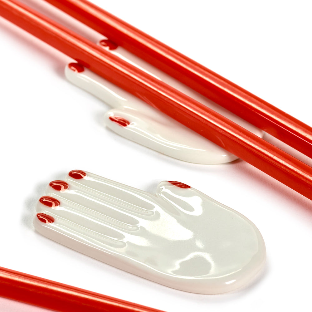 Red chopsticks with a white hand-shaped holder on a white background