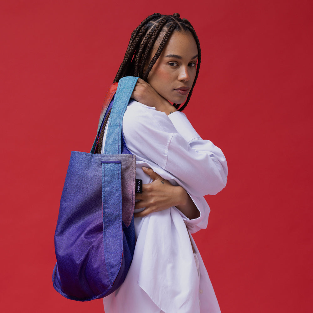 Model holding bag over shoulder.