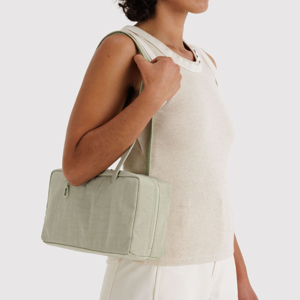 Person holding a light green handbag against a white background