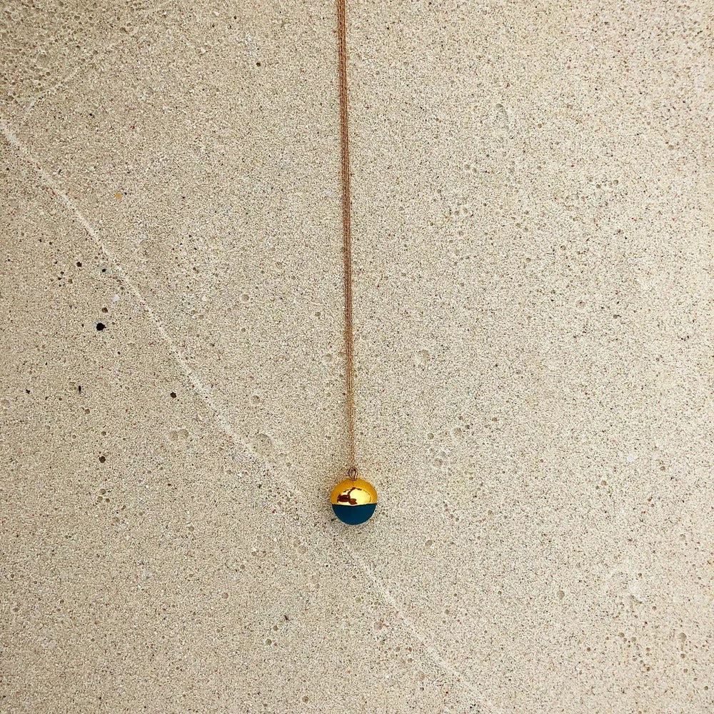 Gold Dipped Pearl Necklace: Black against a concrete wall