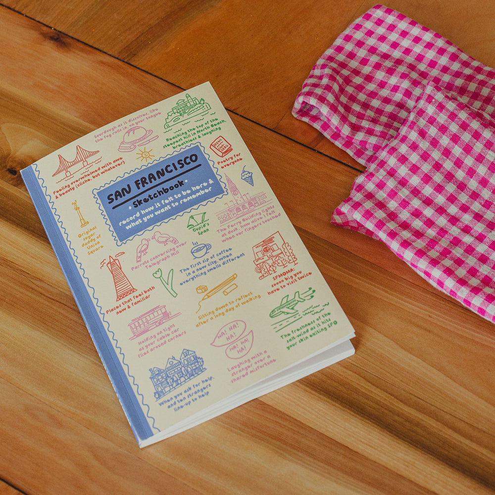 San Francisco-themed notebook on a wooden surface with a pink checkered cloth.