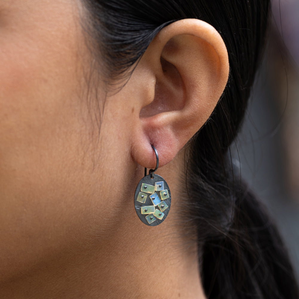 Close-up of an ear wearing a decorative earring with a blurred background