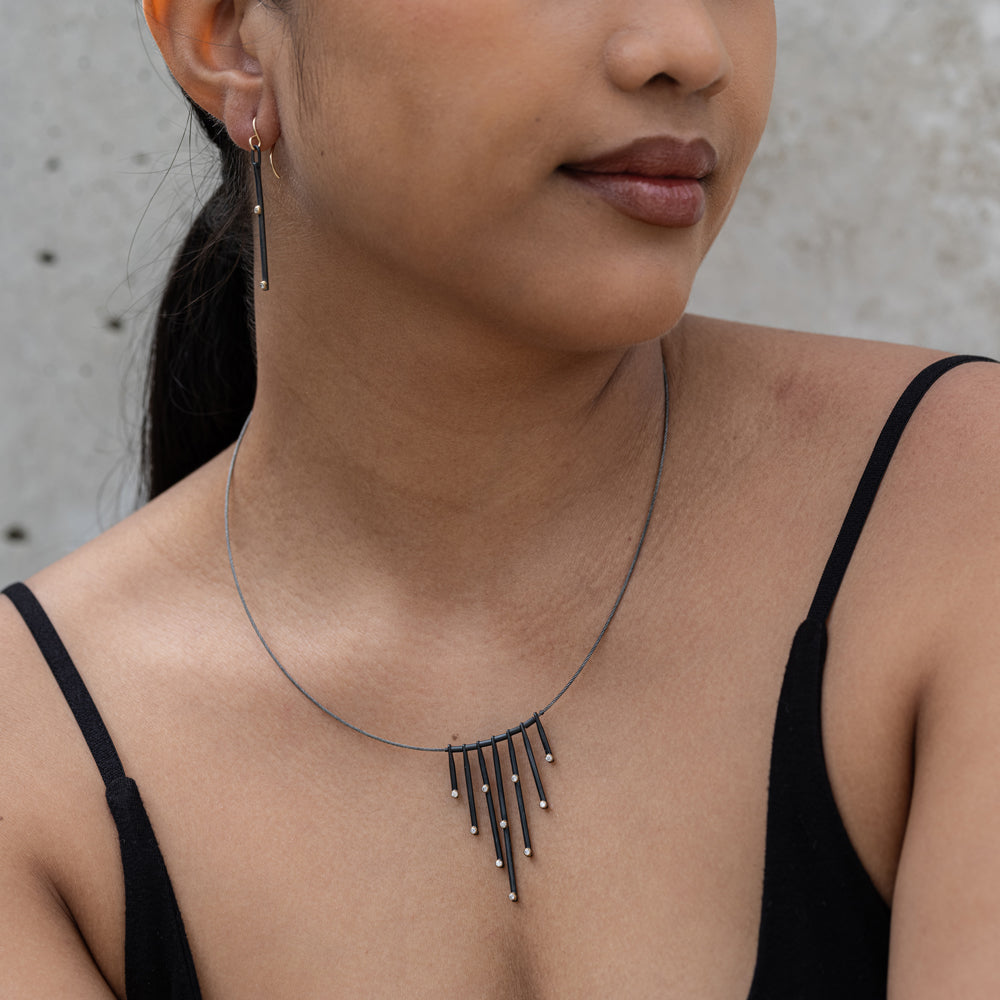 Woman wearing a delicate necklace with a neutral background