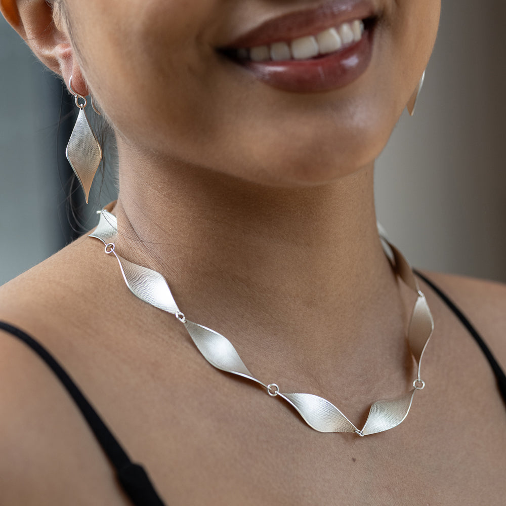 Silver necklace worn by a person with a blurred background
