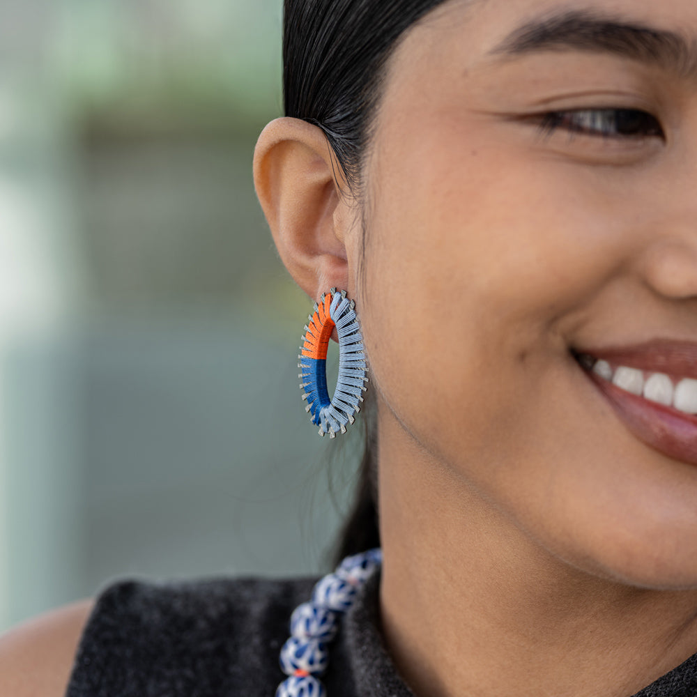 Pair of earrings with coral and blue threaded design on a white background