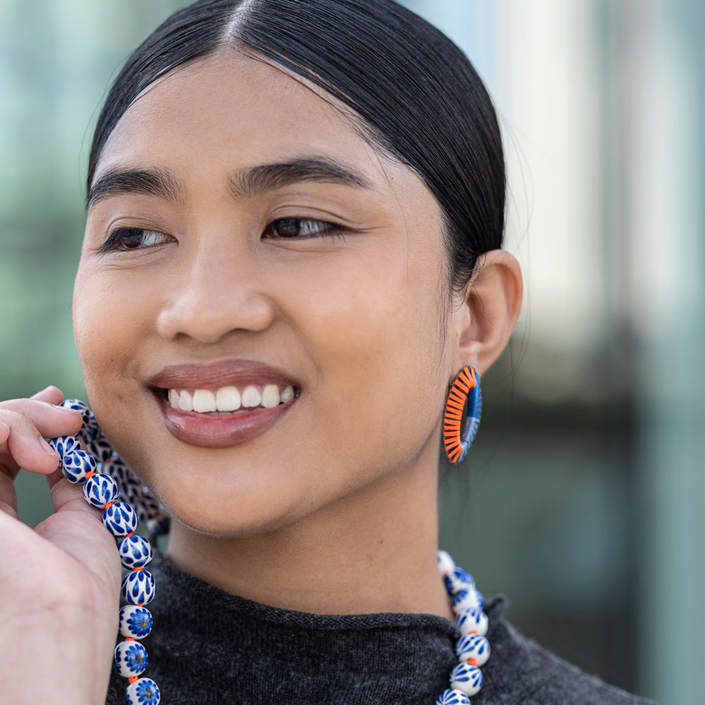 Woman wearing colorful earrings with a blurred outdoor background