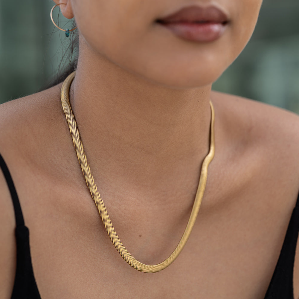 Close-up of a person wearing a gold necklace with a blurred background