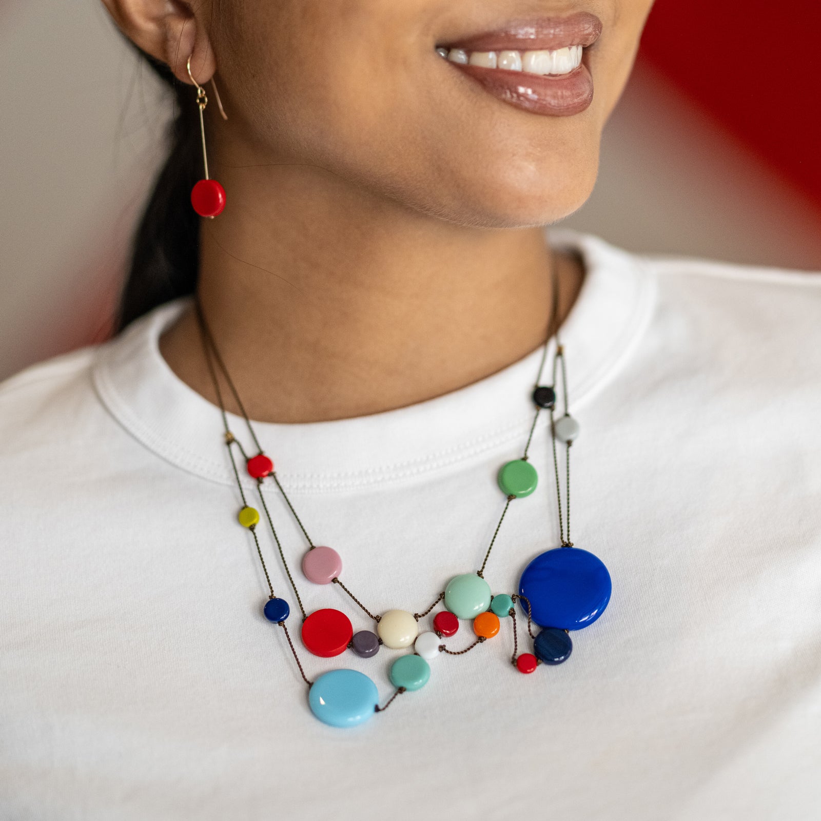 Colorful necklace with multicolored beads worn by a person on a white background