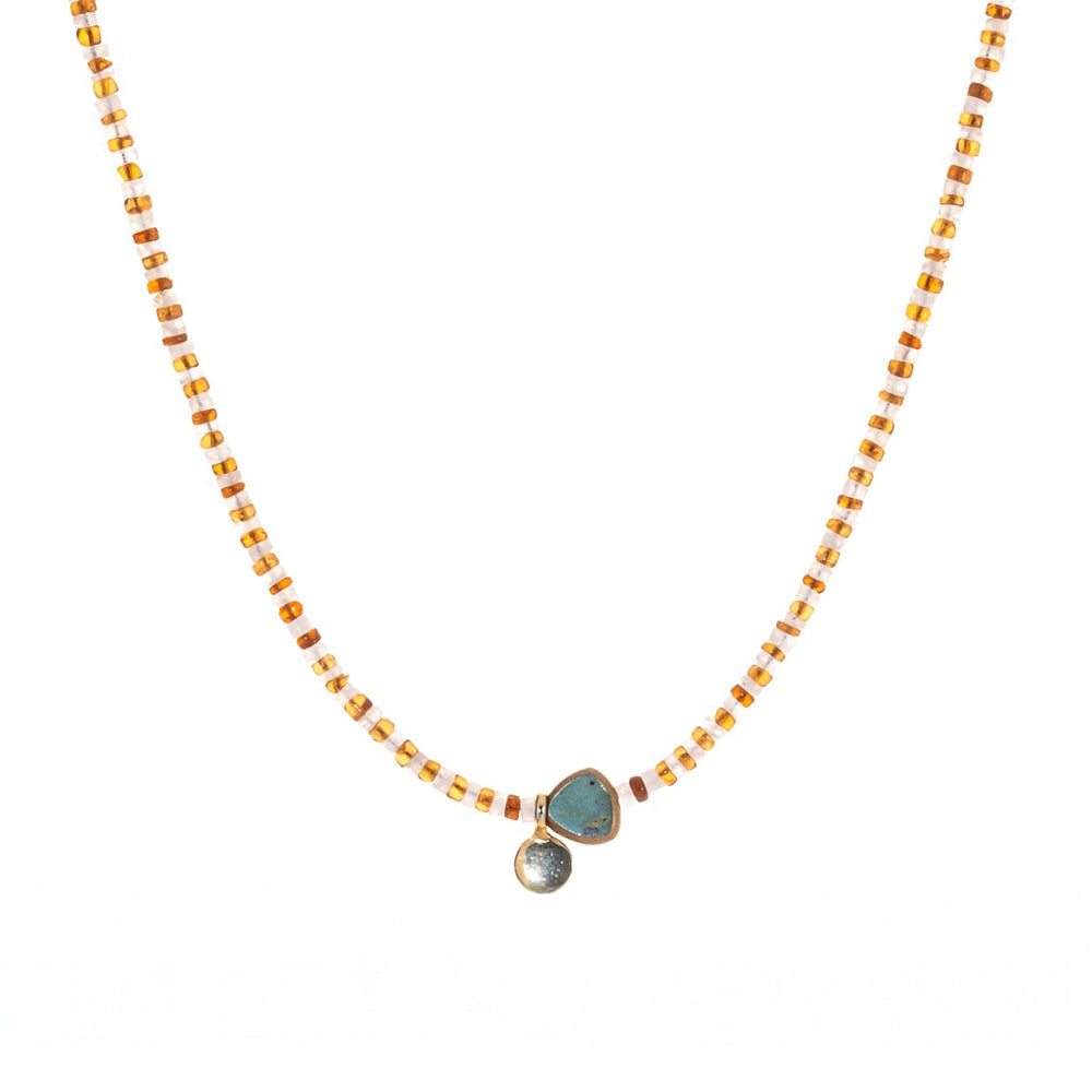 Necklace with gold beads and a stone pendant on a white background