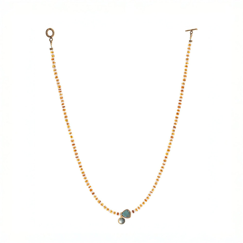 Necklace with gold beads and a stone pendant on a white background