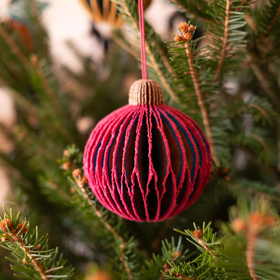 Pink and blue striped Christmas ornament hanging on a tree branch