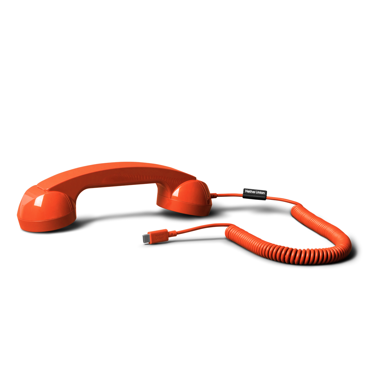 Red phone handset with coiled cable on a white background