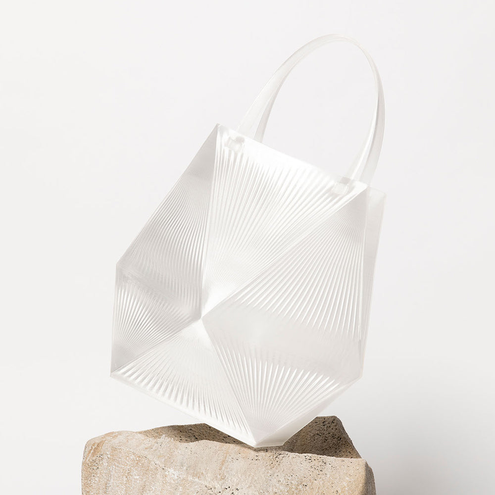 Modern clear tote on a stone base against a white background