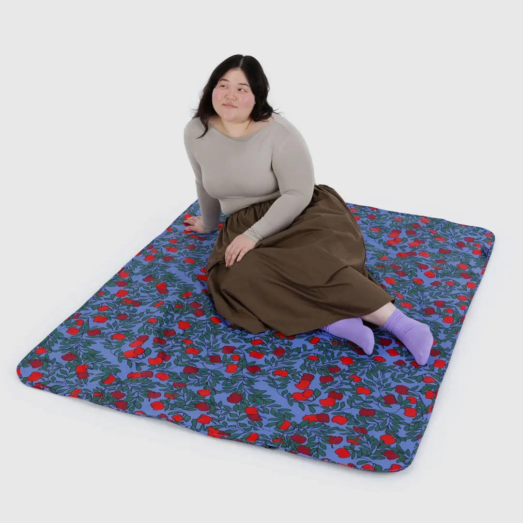 Woman sitting on a colorful blanket with an apple pattern