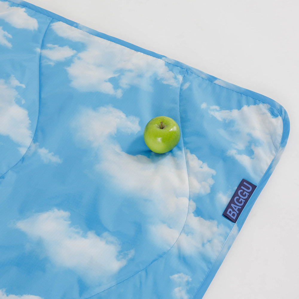 Baggu Picnic Blanket with cloud print folded up and held closed by velcro straps.