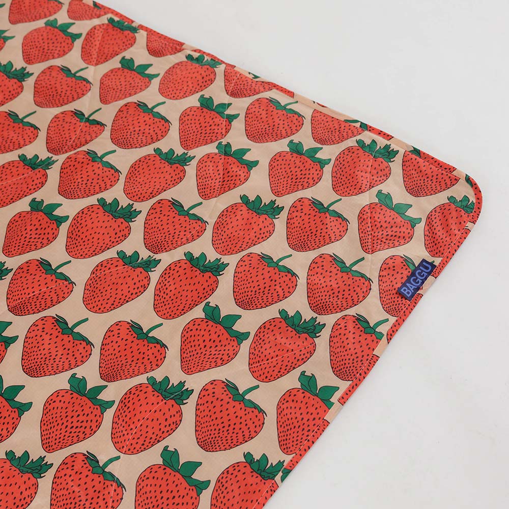 Baggu Strawberry picnic blanket unfurled, corner tag detail.