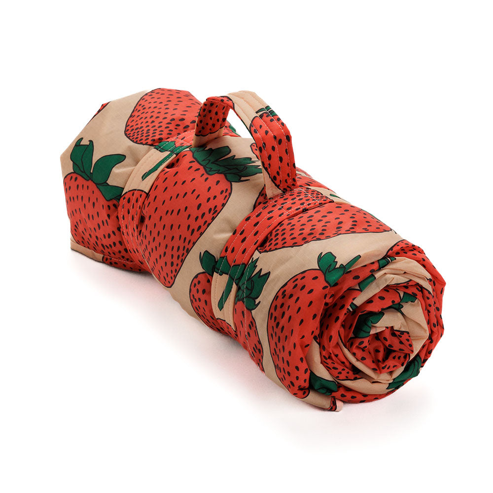 Baggu Picnic Blanket with strawberry print folded up and held closed by velcro straps.