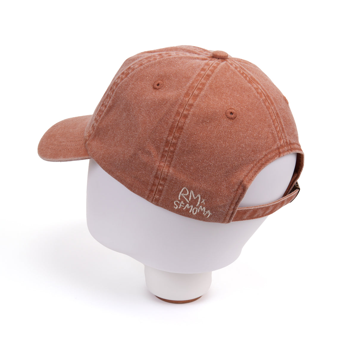 A washed terracotta brown baseball cap displayed on a white mannequin head, showing the side and back view with a small white embroidered logo.